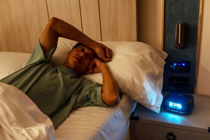 man in bed late trying to sleep suffering insomnia, sleepless or scared in a nightmare, looking sad worried and stressed. Tired and headache or migrai